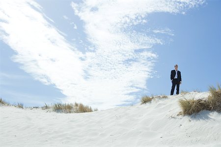 en la cima del mundo - Businessman standing on dune with hands in pockets, low angle view Foto de stock - Sin royalties Premium, Código: 633-01574594