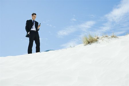 simsearch:633-01574593,k - Businessman standing on dune, looking down at cell phone Stock Photo - Premium Royalty-Free, Code: 633-01574596