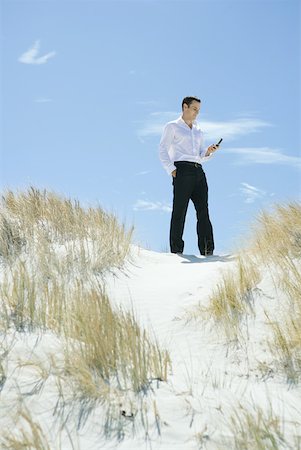 simsearch:633-01574593,k - Businessman standing on dune, looking down at cell phone Stock Photo - Premium Royalty-Free, Code: 633-01574597