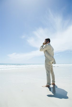 simsearch:633-01574593,k - Barefoot businessman standing on beach, using cell phone Stock Photo - Premium Royalty-Free, Code: 633-01574607