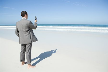 simsearch:632-03500777,k - Barefoot businessman standing on beach, holding up cell phone Foto de stock - Royalty Free Premium, Número: 633-01574618