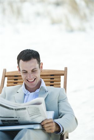 simsearch:633-01713826,k - Businessman sitting in lounge chair, reading newspaper, smiling Stock Photo - Premium Royalty-Free, Code: 633-01574628