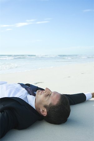 simsearch:633-01713895,k - Homme d'affaires allongé sur le sable, les yeux fermés, souriant Photographie de stock - Premium Libres de Droits, Code: 633-01574631