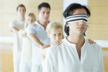 Thérapie de groupe, debout dans la ligne de fichier unique avec les mains sur les épaules de l'autre, homme au plomb les yeux bandé Photographie de stock - Premium Libres de Droits, Code: 633-01574683