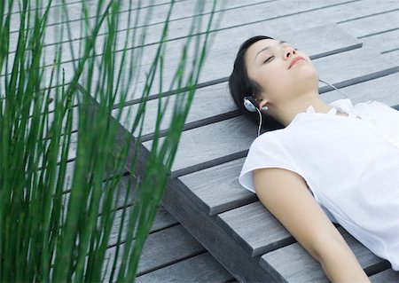 simsearch:633-01572611,k - Woman lying on decking listening to headphones Stock Photo - Premium Royalty-Free, Code: 633-01572566