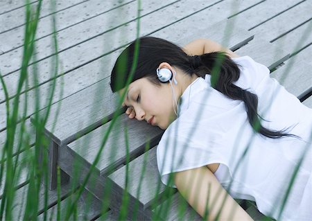 picture of lady on sleeping lounge chair - Woman lying on decking listening to headphones Stock Photo - Premium Royalty-Free, Code: 633-01572567