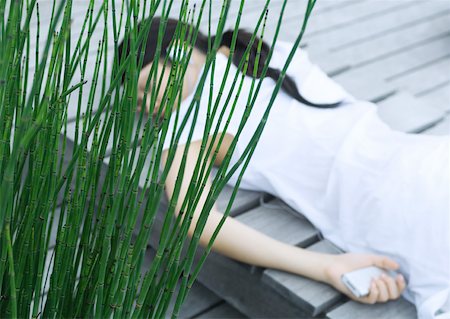 picture of lady on sleeping lounge chair - Woman lying on decking listening to headphones Stock Photo - Premium Royalty-Free, Code: 633-01572568
