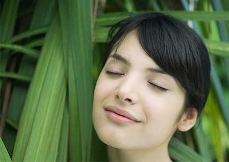 simsearch:633-01572611,k - Woman standing in lush foliage, eyes closed, smiling Stock Photo - Premium Royalty-Free, Code: 633-01572641