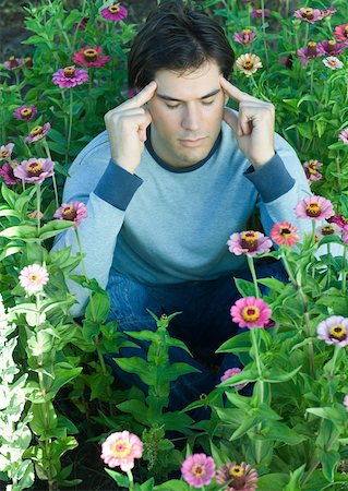 simsearch:633-01572737,k - Man sitting in flowers, eyes closed and hands on temples Foto de stock - Royalty Free Premium, Número: 633-01572726
