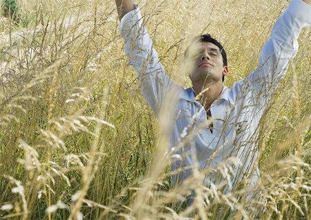 simsearch:633-01572737,k - Man standing in field, raising arms, eyes closed Foto de stock - Royalty Free Premium, Número: 633-01572749