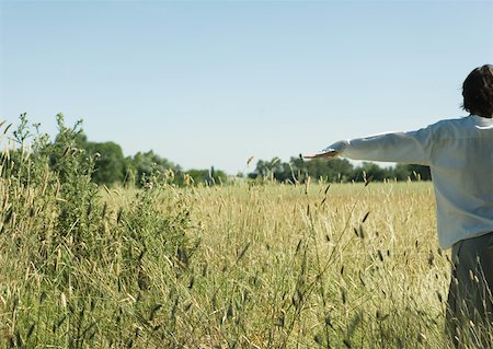 Young male standing in field, arms out, rear view Stock Photo - Premium Royalty-Free, Code: 633-01572775