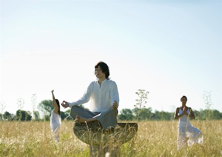 Young male and females doing yoga in field Stock Photo - Premium Royalty-Free, Code: 633-01572795