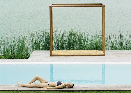 simsearch:633-01573950,k - Femme sur la terrasse au bord de piscine, lac en arrière-plan Photographie de stock - Premium Libres de Droits, Code: 633-01572862