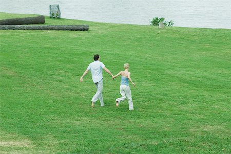 simsearch:695-03373971,k - Couple running across grass, hand in hand, full length, high angle view Foto de stock - Royalty Free Premium, Número: 633-01573116