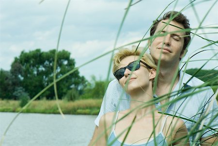 Couple by lake, woman wearing sunglasses, man closing eyes, portrait Stock Photo - Premium Royalty-Free, Code: 633-01573127