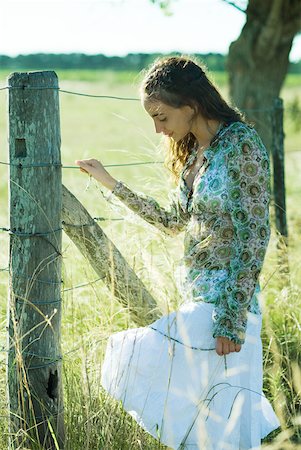 simsearch:632-01277362,k - Jeune femme debout à côté de la clôture rurale, regardant vers le bas Photographie de stock - Premium Libres de Droits, Code: 633-01573222