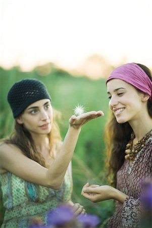 Two young women outdoors, one holding dandelion seed head on palm of hand Stock Photo - Premium Royalty-Free, Code: 633-01573284