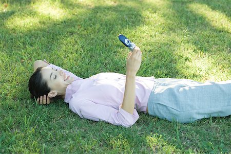 simsearch:633-01574593,k - Businesswoman lying in grass, looking at cell phone, smiling Stock Photo - Premium Royalty-Free, Code: 633-01573545