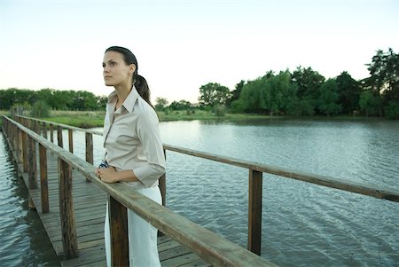 simsearch:633-01573622,k - Woman standing on wooden footbridge over lake, looking into distance Foto de stock - Royalty Free Premium, Número: 633-01573575