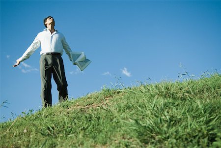 Businessman standing on grassy hill, arms out, head back and eyes closed, low angle view Stock Photo - Premium Royalty-Free, Code: 633-01573579