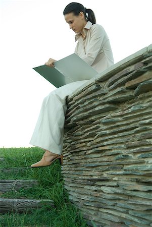 simsearch:632-01271843,k - Businesswoman sitting on stone wall, studying file Stock Photo - Premium Royalty-Free, Code: 633-01573572