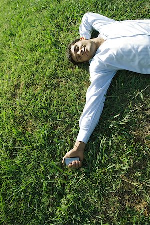 simsearch:633-01574322,k - Businessman lying on grass, holding cell phone, eyes closed, smiling Stock Photo - Premium Royalty-Free, Code: 633-01573581