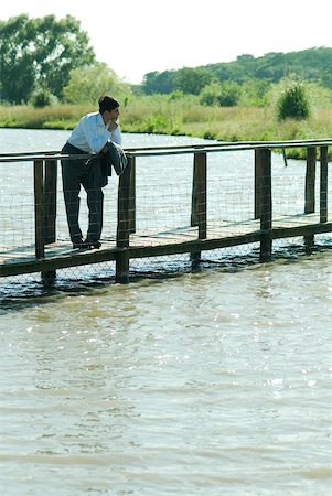 simsearch:633-01573622,k - Businessman on wooden footbridge over lake, looking away Fotografie stock - Premium Royalty-Free, Codice: 633-01573604