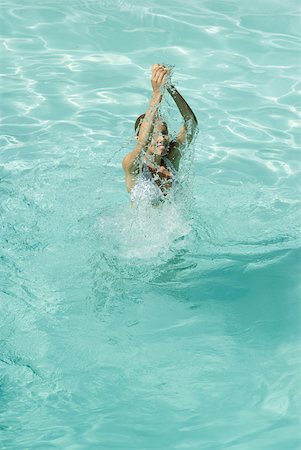 simsearch:633-01573892,k - Young woman standing in pool, splashing with arms over head, full length, high angle view Stock Photo - Premium Royalty-Free, Code: 633-01573860