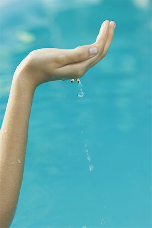 person cupping water - Young woman holding up cupped hand full of water, cropped view Stock Photo - Premium Royalty-Free, Code: 633-01573889
