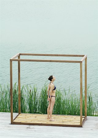 simsearch:633-01573944,k - Young woman standing inside square structure, next to body of water Stock Photo - Premium Royalty-Free, Code: 633-01573935