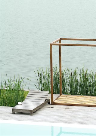 Lounge chair on deck between pool and body of water Stock Photo - Premium Royalty-Free, Code: 633-01573948