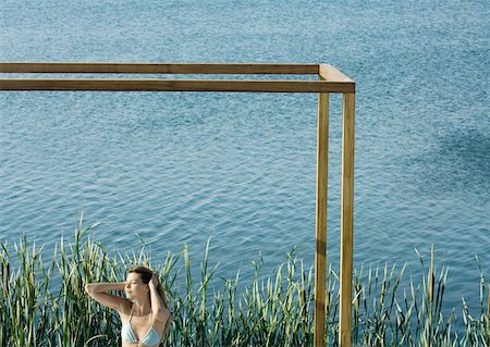 simsearch:649-08479729,k - Young woman standing inside square structure, next to body of water Stock Photo - Premium Royalty-Free, Code: 633-01573979