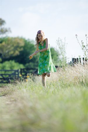 simsearch:633-01714195,k - Young woman in sundress walking through rural field, holding flower Stock Photo - Premium Royalty-Free, Code: 633-01714090