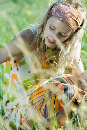 Young woman sitting in field of flowers, looking down, cropped view Stock Photo - Premium Royalty-Free, Code: 633-01714121