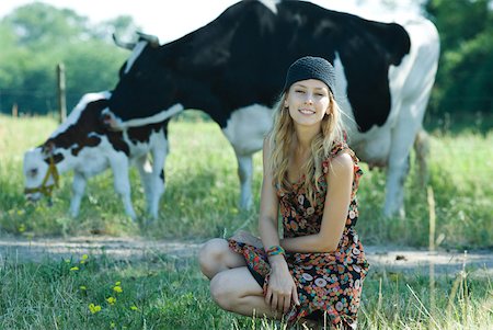 Young woman crouching in front of cows, smiling at camera Stock Photo - Premium Royalty-Free, Code: 633-01714159