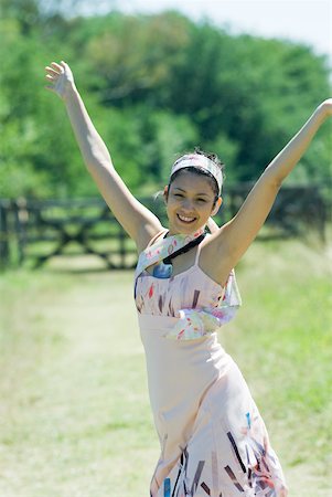 simsearch:633-01714195,k - Young woman standing with arms raised in rural setting, smiling at camera Stock Photo - Premium Royalty-Free, Code: 633-01714199