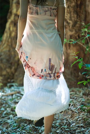 simsearch:633-01715215,k - Jeune femme qui marche dans les bois, soulevant la jupe, recadrée vue arrière Photographie de stock - Premium Libres de Droits, Code: 633-01714207