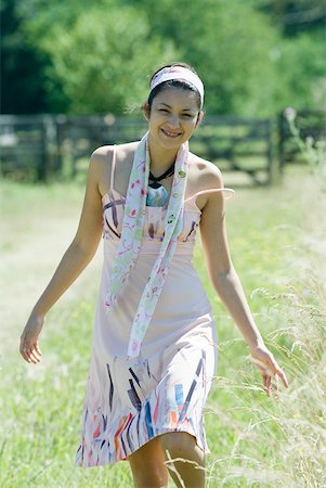 simsearch:633-01714195,k - Young woman walking in rural setting, smiling at camera Stock Photo - Premium Royalty-Free, Code: 633-01714200