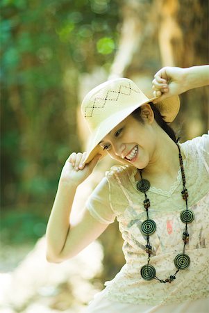 simsearch:633-01714195,k - Young woman standing outdoors, putting on sunhat, smiling Stock Photo - Premium Royalty-Free, Code: 633-01714216