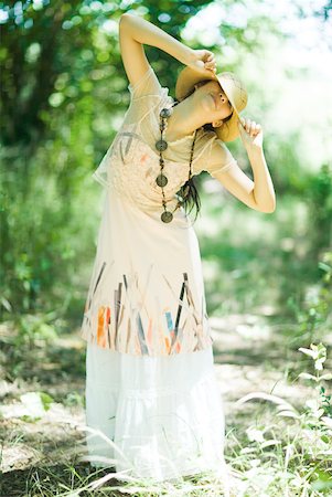 simsearch:633-01714195,k - Young woman standing in woods, pulling sunhat over eyes Stock Photo - Premium Royalty-Free, Code: 633-01714221