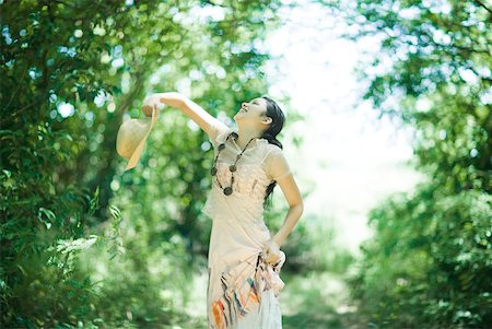 simsearch:633-01714195,k - Young woman standing in woods, throwing up sunhat Stock Photo - Premium Royalty-Free, Code: 633-01714222