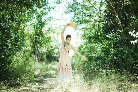simsearch:633-01714195,k - Young woman standing in woods with arm raised, holding up sunhat Stock Photo - Premium Royalty-Free, Code: 633-01714223