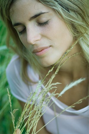 simsearch:633-01572611,k - Young woman holding tall grass, eyes closed, close-up Stock Photo - Premium Royalty-Free, Code: 633-01714259