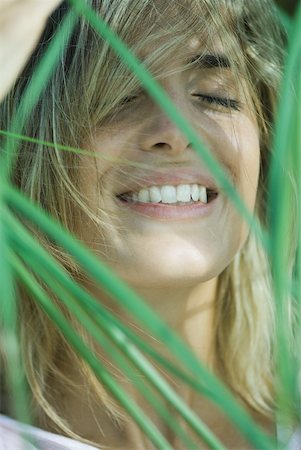 simsearch:633-01572611,k - Young woman among foliage, hair in face, smiling, eyes closed Stock Photo - Premium Royalty-Free, Code: 633-01714266