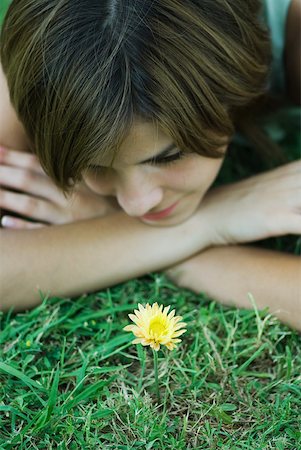 simsearch:633-01992734,k - Young woman lying on grass looking at flower, head resting on arms, cropped view Foto de stock - Royalty Free Premium, Número: 633-01714268