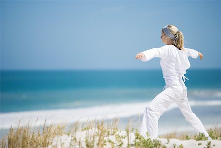 simsearch:633-01714395,k - Young woman standing on dunes, exercising, ocean in background Foto de stock - Sin royalties Premium, Código: 633-01714375