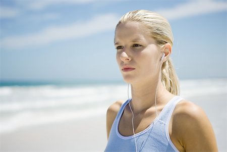 Young woman in active wear wearing earphones on beach, head and shoulders Stock Photo - Premium Royalty-Free, Code: 633-01714381