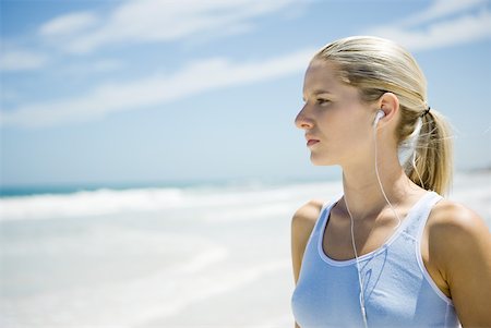 Young woman in active wear wearing earphones on beach, head and shoulders Stock Photo - Premium Royalty-Free, Code: 633-01714382