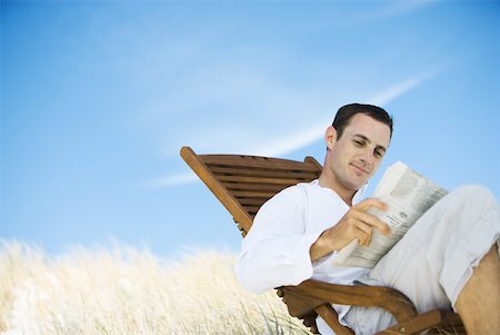 simsearch:633-01713826,k - Young man sitting in deck chair, reading newspaper Stock Photo - Premium Royalty-Free, Code: 633-01714426