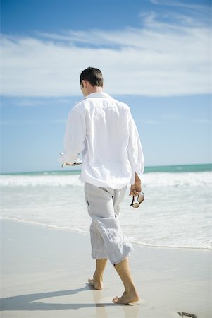 Young man walking on beach, rear view Stock Photo - Premium Royalty-Free, Code: 633-01714444